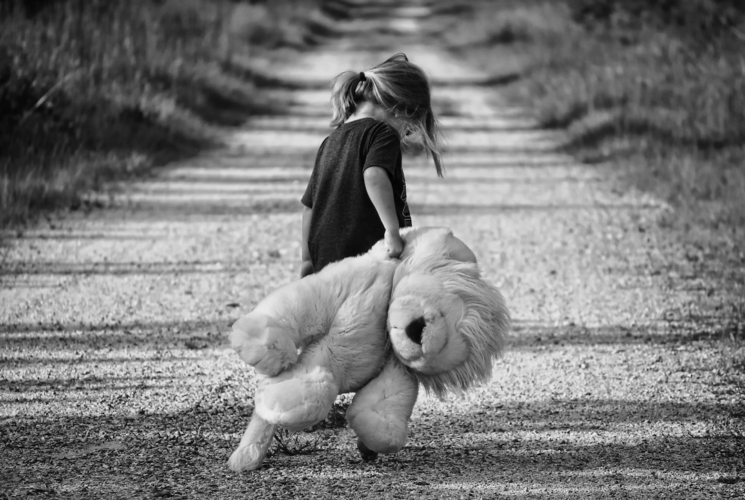 Child Custody A child walking down a path with her stuffed animal in tow, in greyscale, symbolizing the emotional toll custody issues can take on a family.